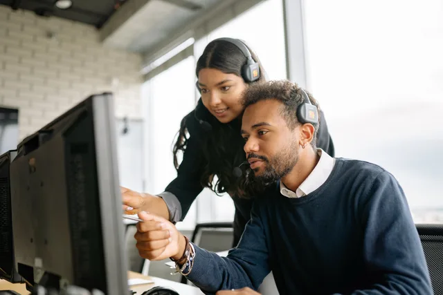 Two call center employees working together with headsets in a modern office setting. Automatyzacja powiadomień w CRM: co można ustawić bez programowania