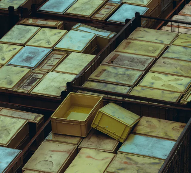 Overhead view of yellow and weathered plastic storage bins arranged neatly. Wymiana danych między ERP, CRM i magazynem: co zaplanować